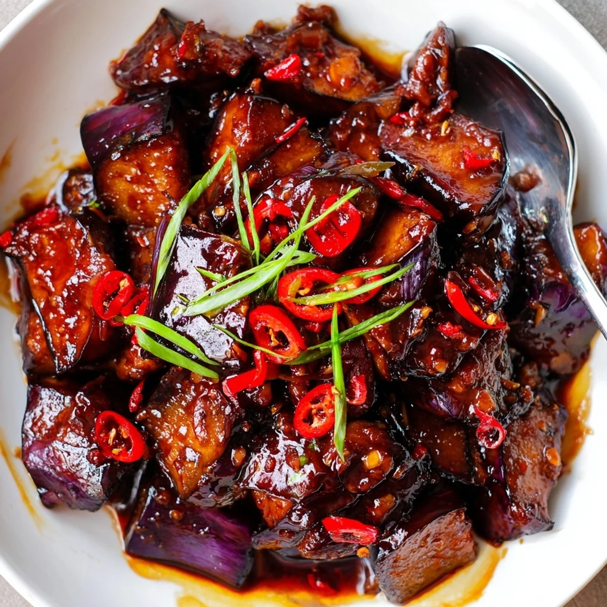 Warm Sichuan Style Braised Aubergines, tender eggplant batons steaming over rice.