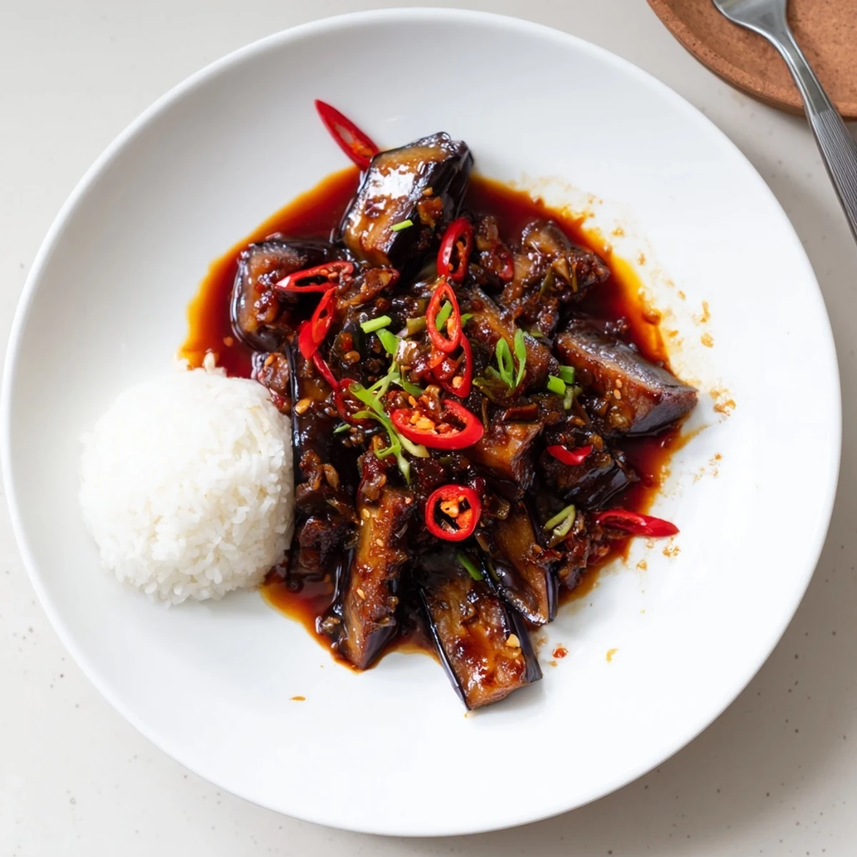 Sichuan Style Braised Aubergines glistening in spicy red sauce, scallions, jasmine rice.