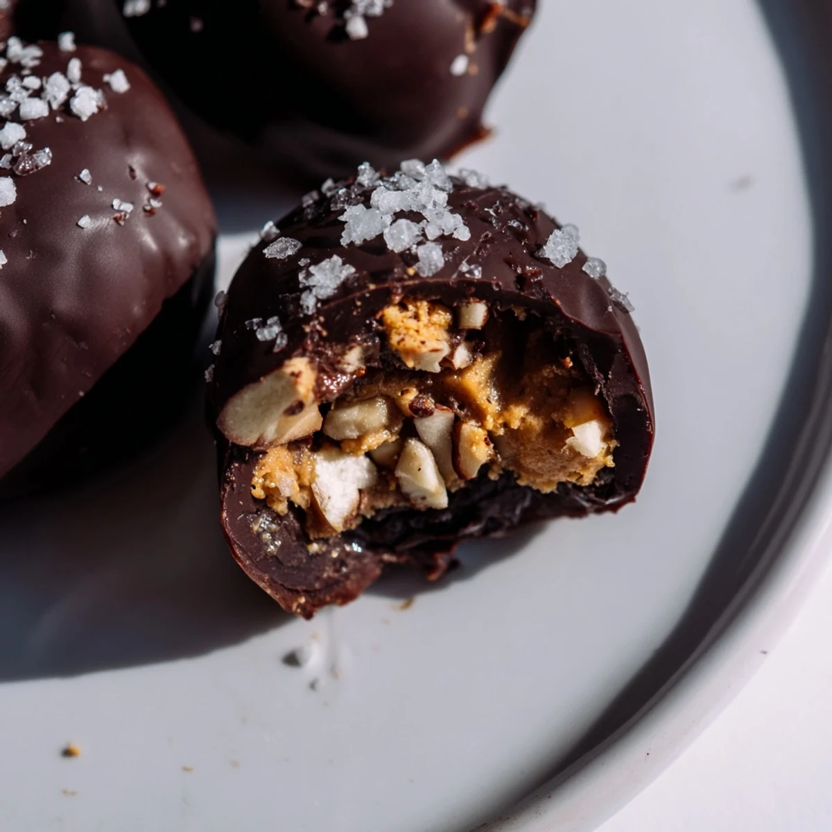 Bite-sized Date Snickers candy alternative with cross-section visible, displaying layers of nut butter and peanuts inside sweet dates