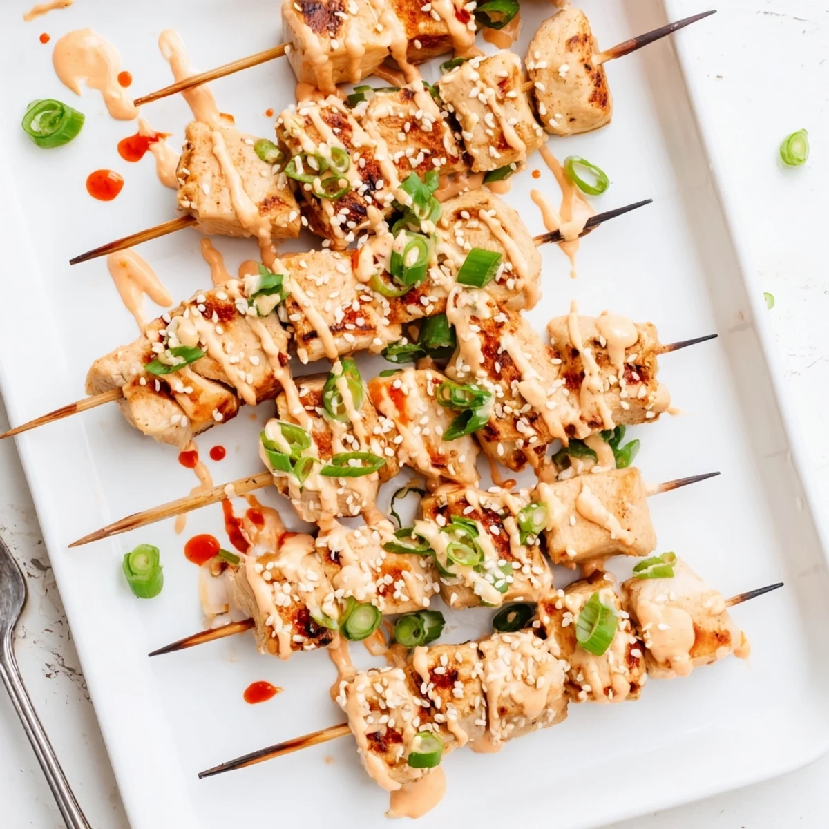 Tender Bang Bang Chicken Skewers coated in sweet chili sriracha sauce on a serving platter