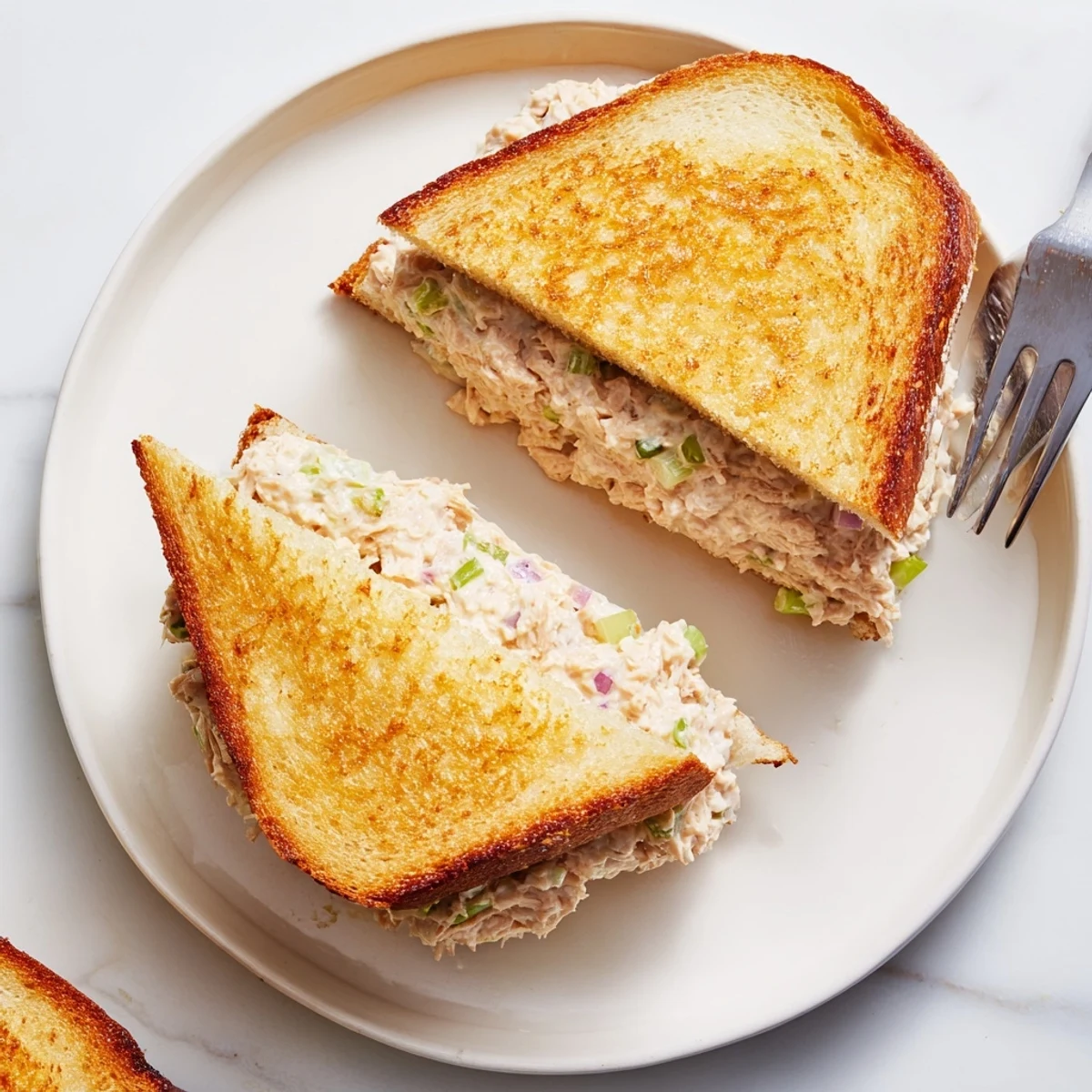 Golden grilled tuna melt sandwich with melted cheese oozing from crispy buttered bread