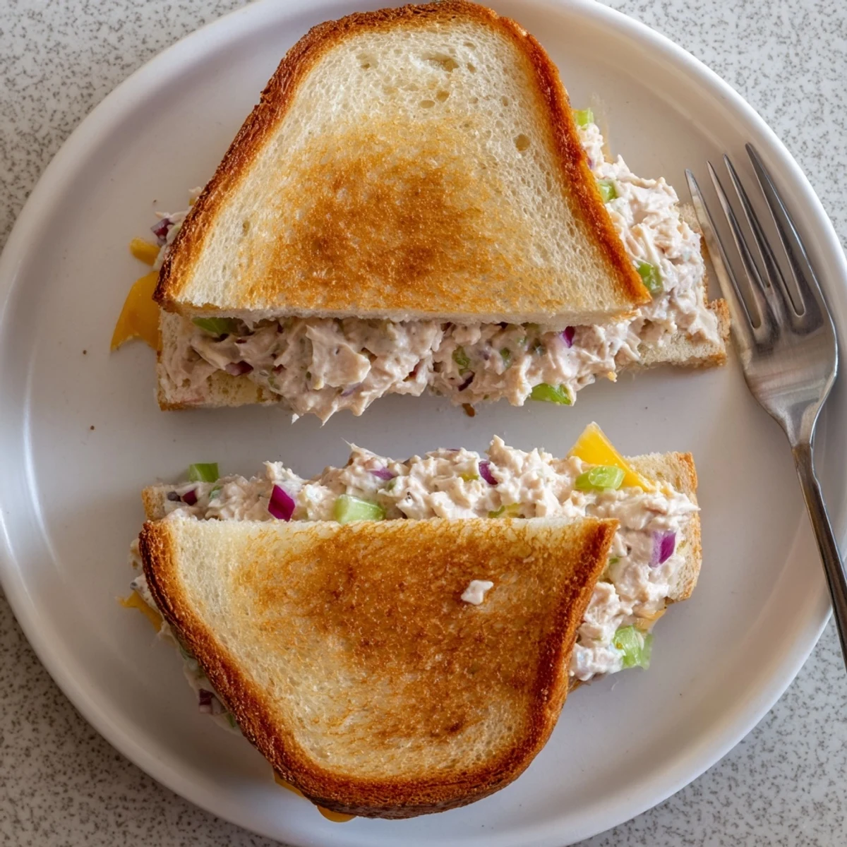 Classic American tuna melt sandwich sliced in half revealing warm tuna salad and melted cheddar cheese