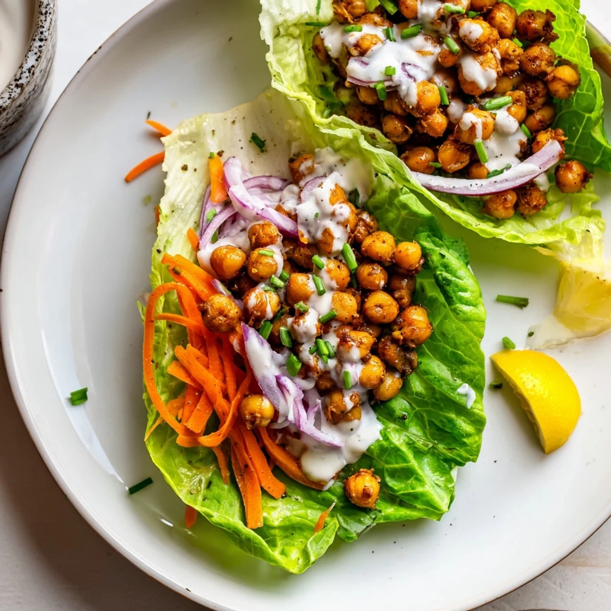 Skillet-heated Buffalo Chickpea Lettuce Wraps topped with cooling vegan ranch drizzle.
