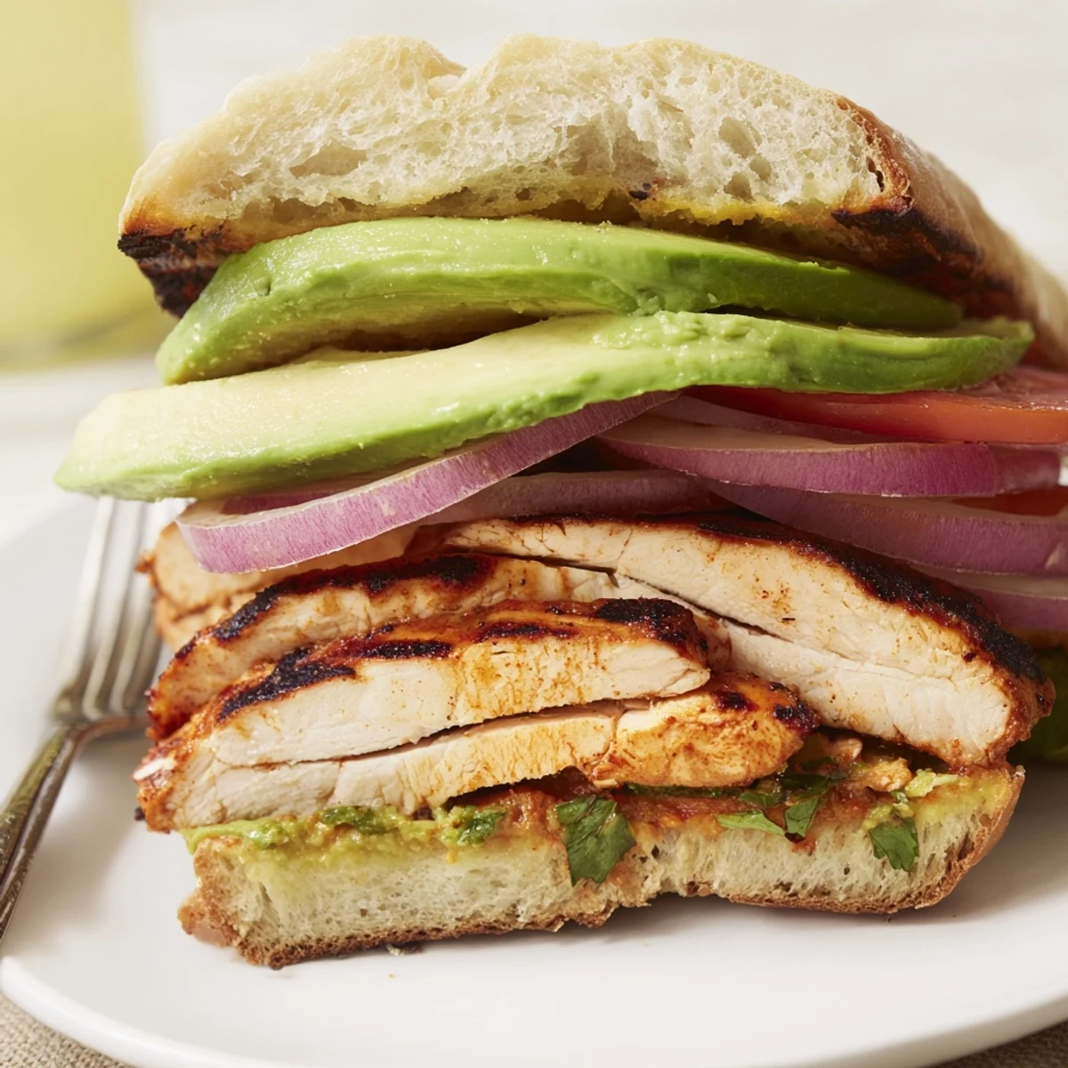Picnic-ready Chipotle Grilled Chicken With Avocado Sandwich served with lime wedge and greens.