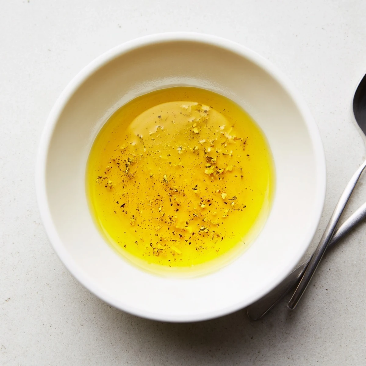 Golden honey mustard vinaigrette drizzled over fresh mixed greens in a white bowl