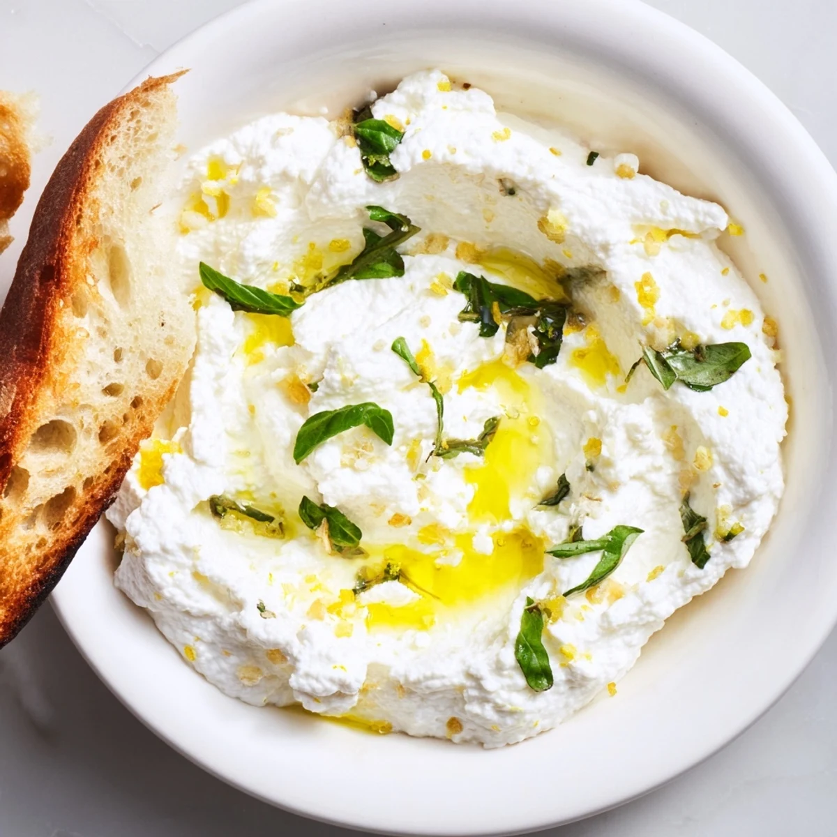 Light and fluffy whipped ricotta cheese drizzled with olive oil and served alongside crispy toasted crostini