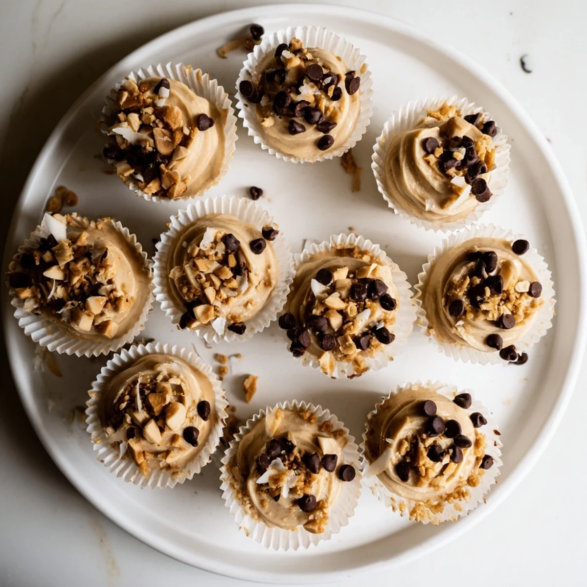 Close up of frozen peanut butter Greek yogurt bites sprinkled with coconut flakes on a marble serving board