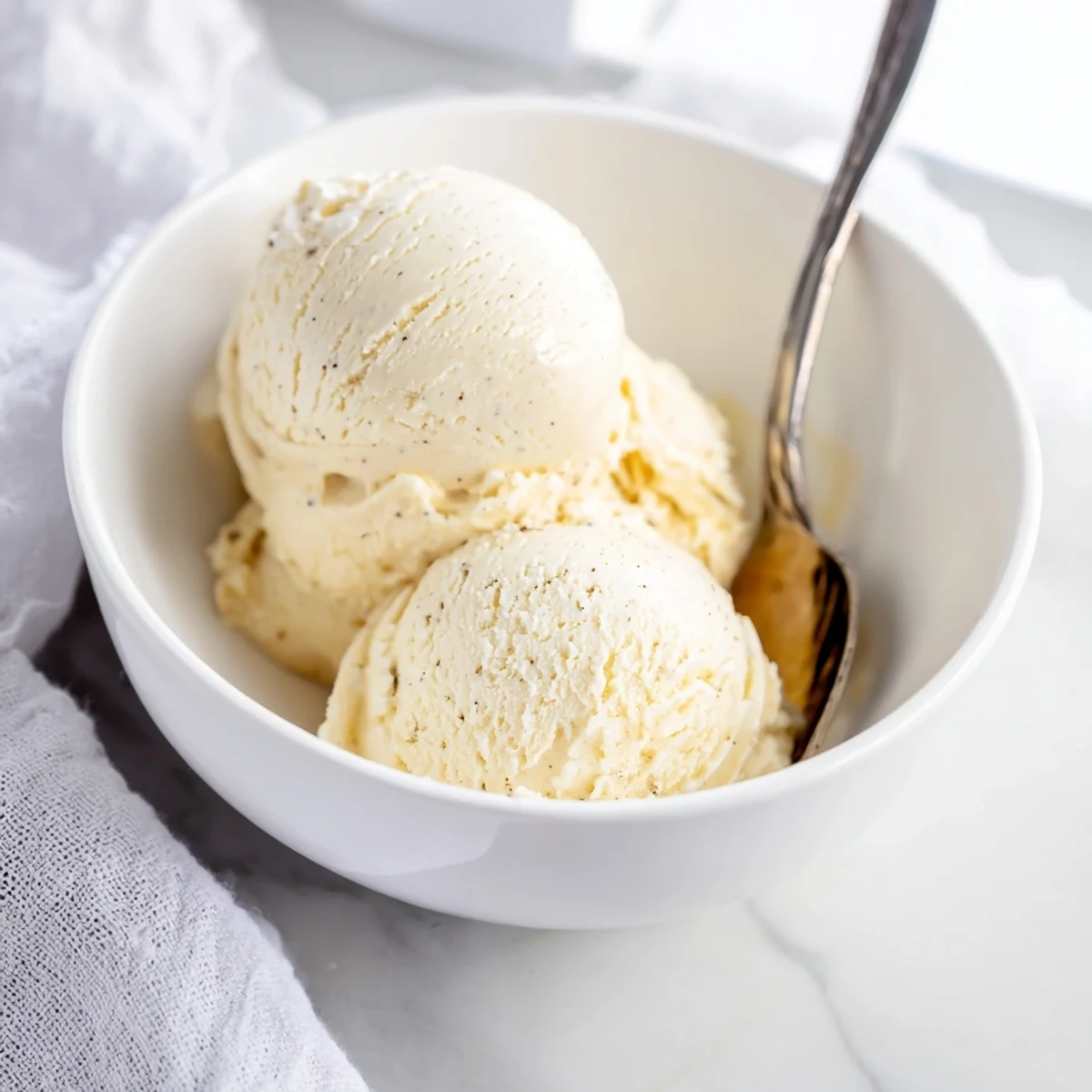 Creamy homemade vanilla ice cream scooped into a glass bowl with fresh berries on top