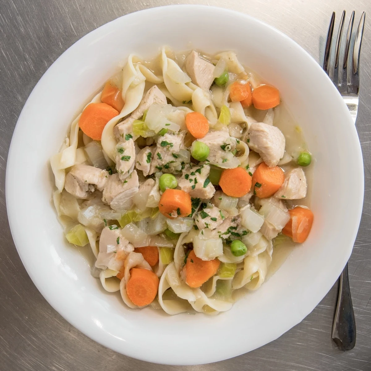 Creamy one pot chicken and noodles in a bowl with tender vegetables and herbs