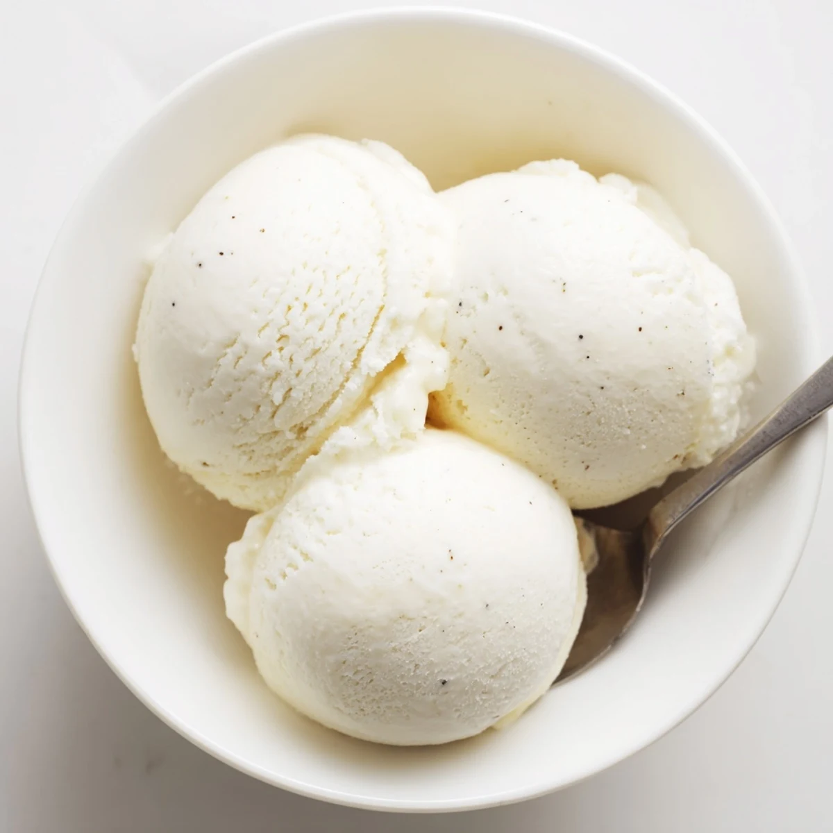 Homemade vanilla ice cream recipe showing smooth creamy scoops in a glass bowl