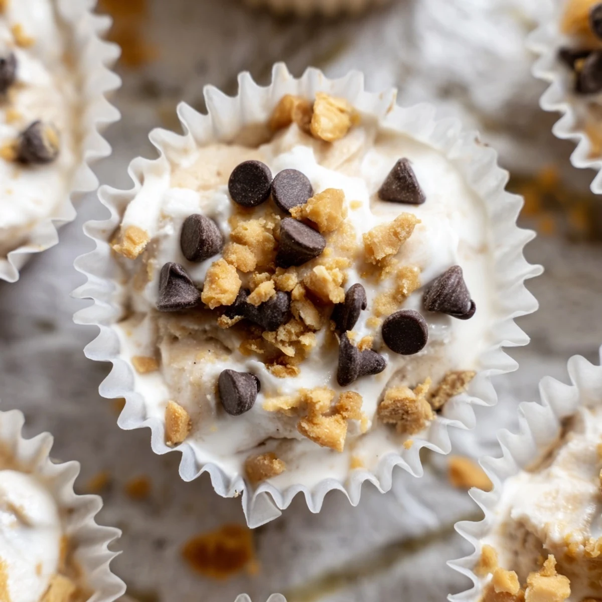 Creamy frozen peanut butter Greek yogurt bites topped with dark chocolate chips in a muffin tin