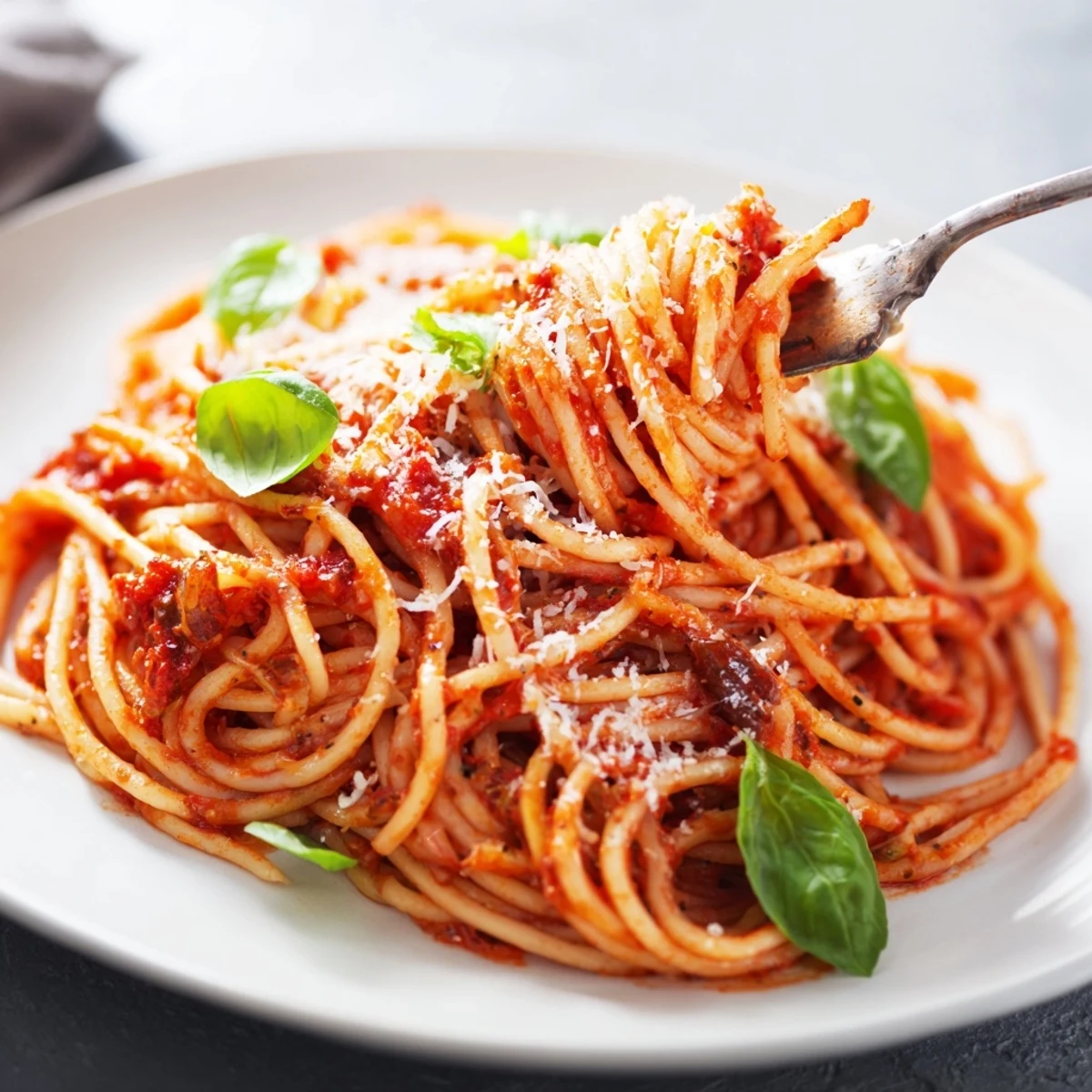 Steaming bowl of classic pasta tossed in rich tomato sauce with fresh basil garnish