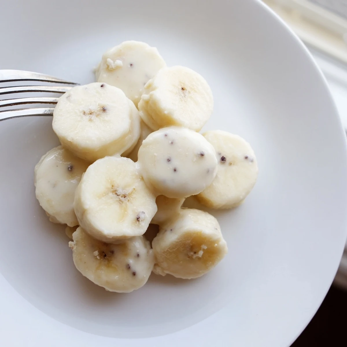 Frozen Banana Yogurt Bites on parchment, creamy coating, sprinkled with mini chips