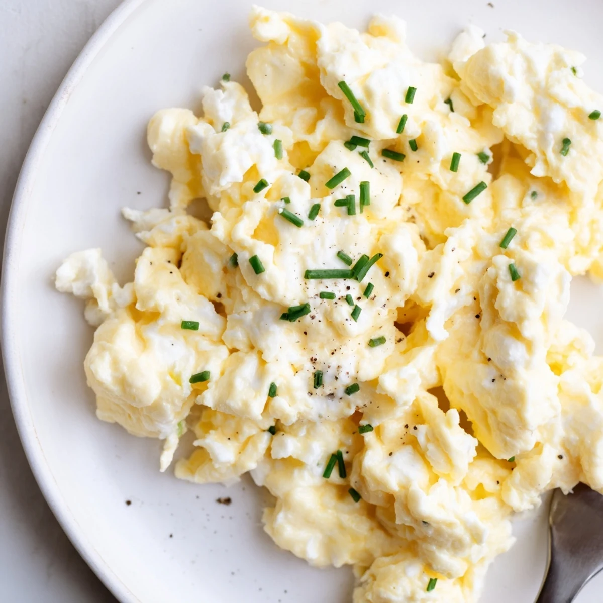 Plated Cottage Cheese Scrambled Eggs with Chives, soft curds, fragrant fresh herbs