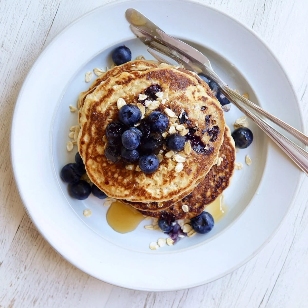 Healthy protein banana pancakes stacked high on a white plate with butter melting