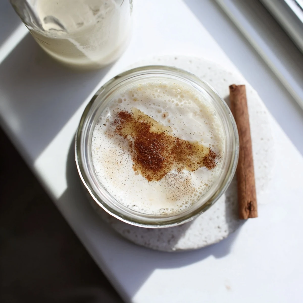 Homemade almond milk pouring from a glass jar into a bowl, showing its smooth creamy white dairy-free texture