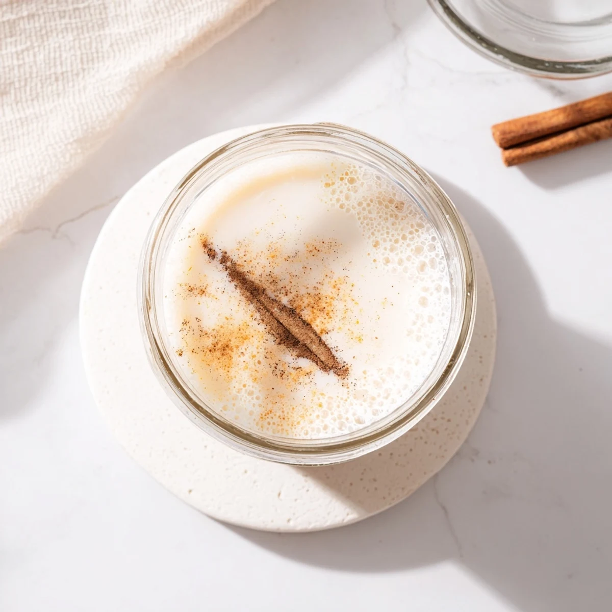 Creamy homemade almond milk in a clear mason jar with vanilla bean and natural light streaming through