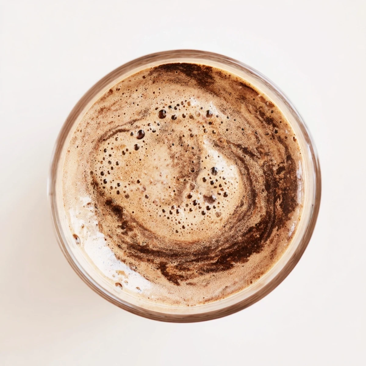Thick raw chocolate banana shake topped with cacao nibs in a clear glass
