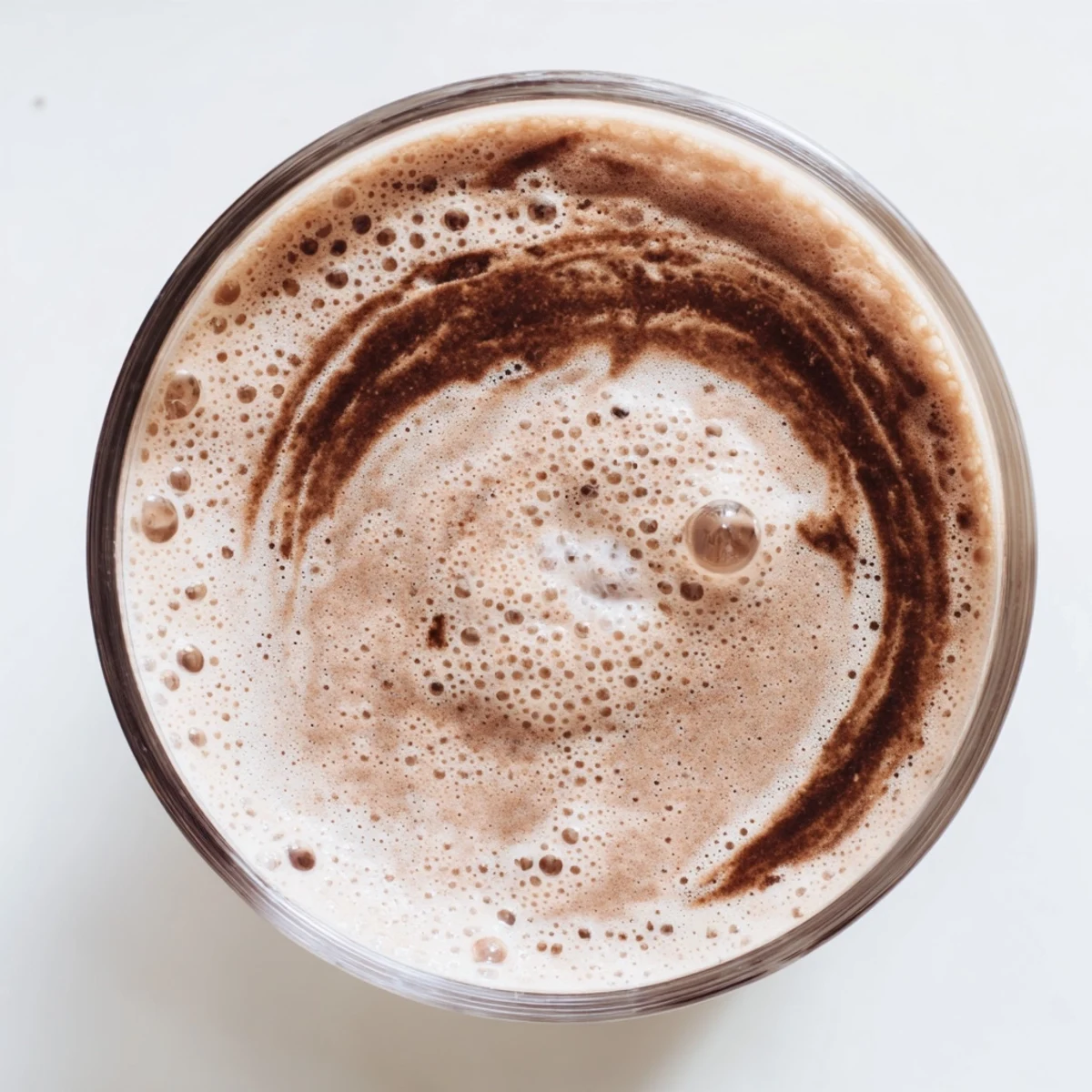 Creamy vegan raw chocolate banana shake garnished with coconut flakes and drizzled chocolate
