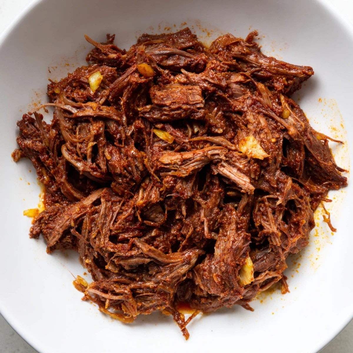 Tender slow cooker beef barbacoa shredded and piled high in a bowl with rich dark juices