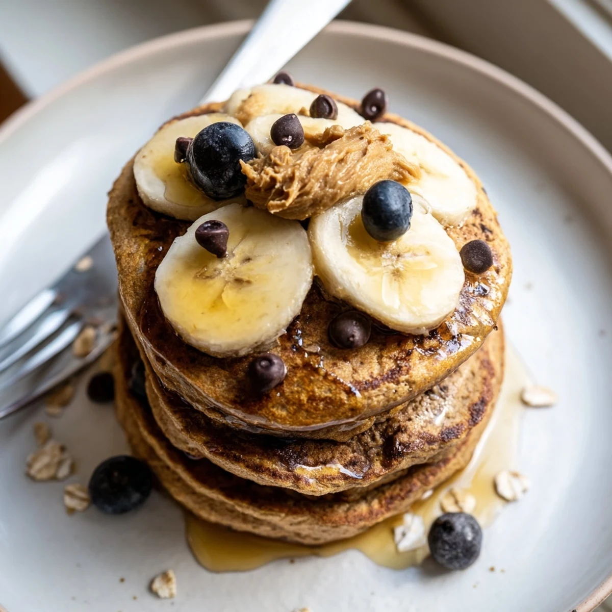 Healthy Protein Banana Pancakes topped with nut butter, berries, and maple drizzle