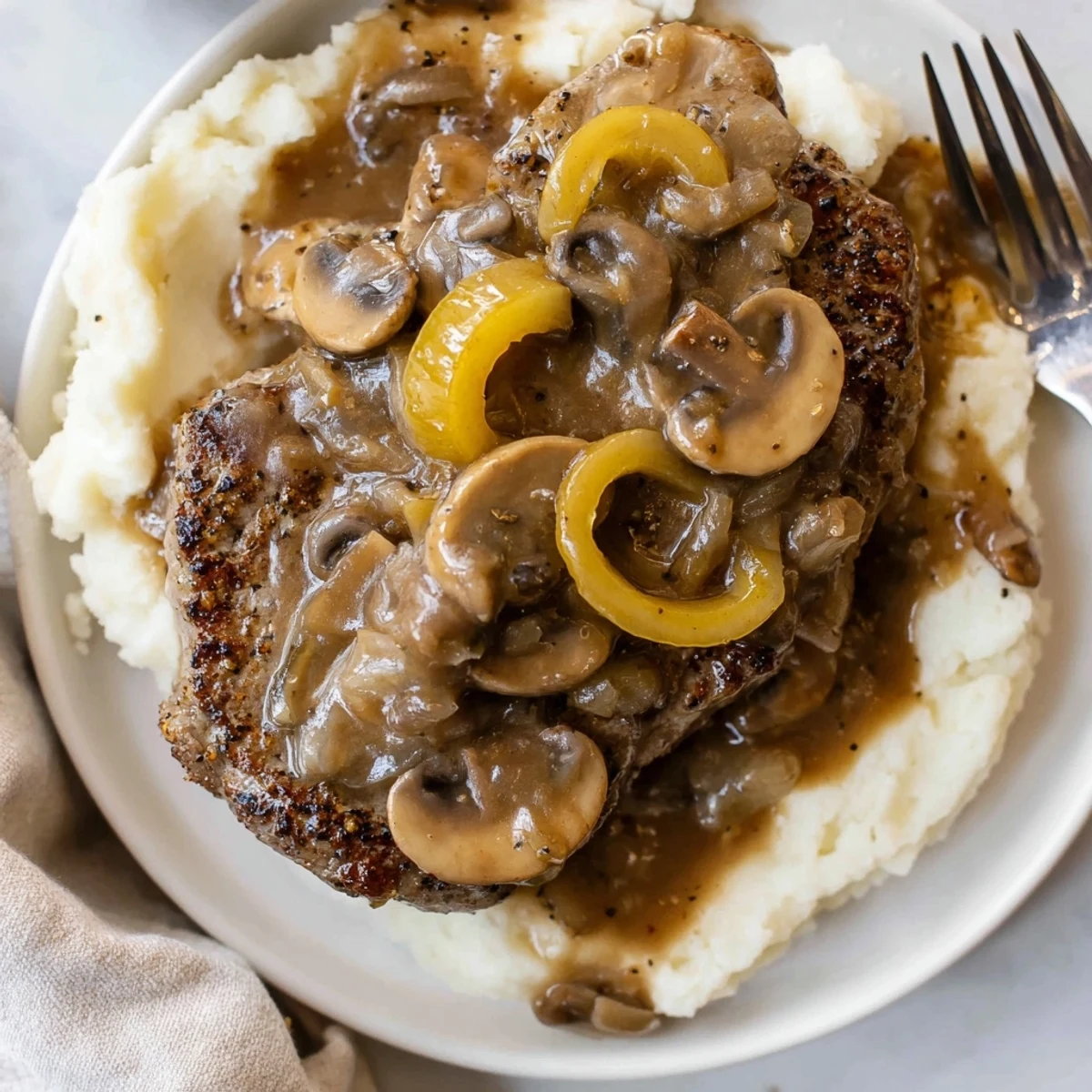 Country Style Smothered Cube Steak Recipe nestled over creamy mashed potatoes, steaming hot