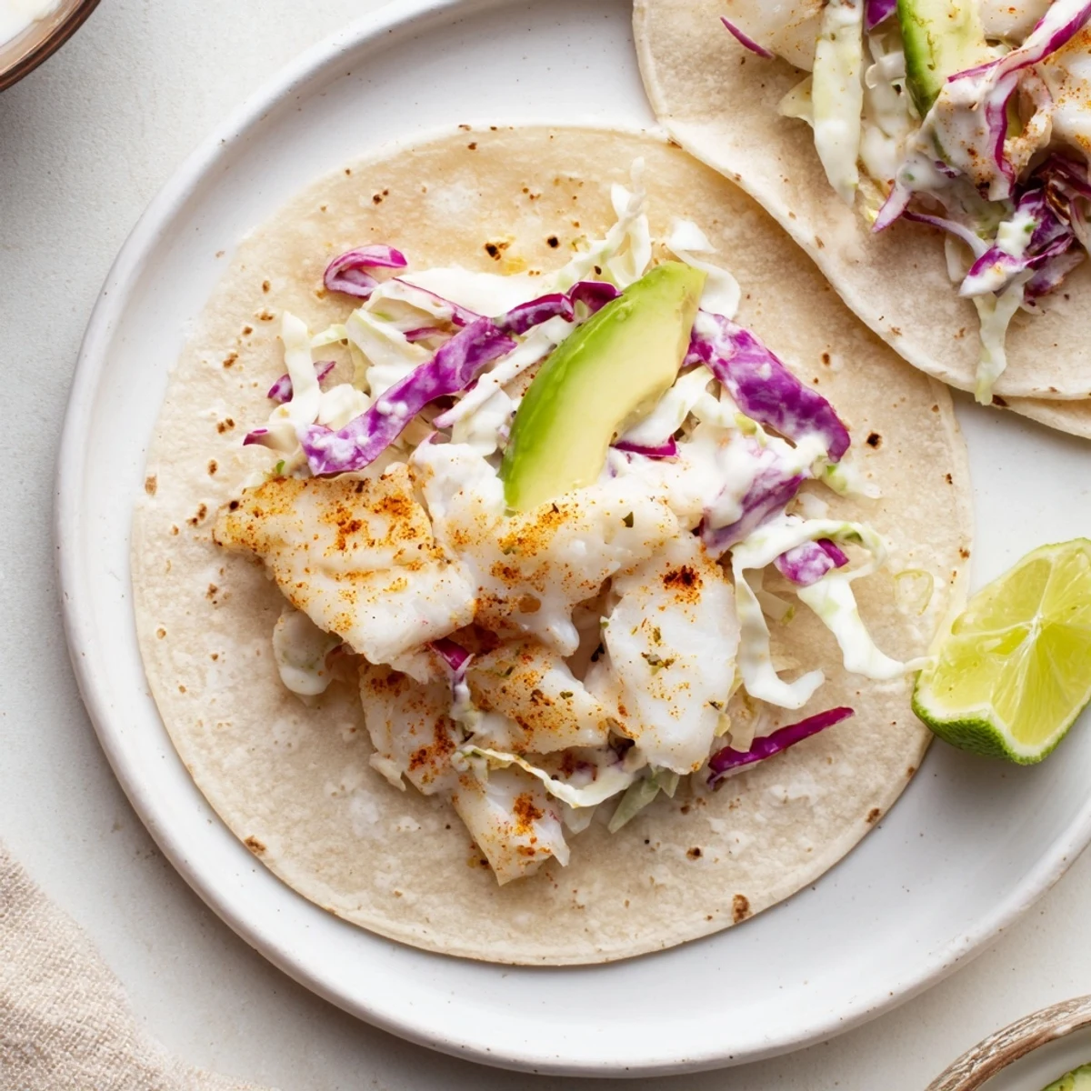 Stacked corn tortillas holding Baked Cod Fish Tacos with Creamy Cilantro Lime Sauce