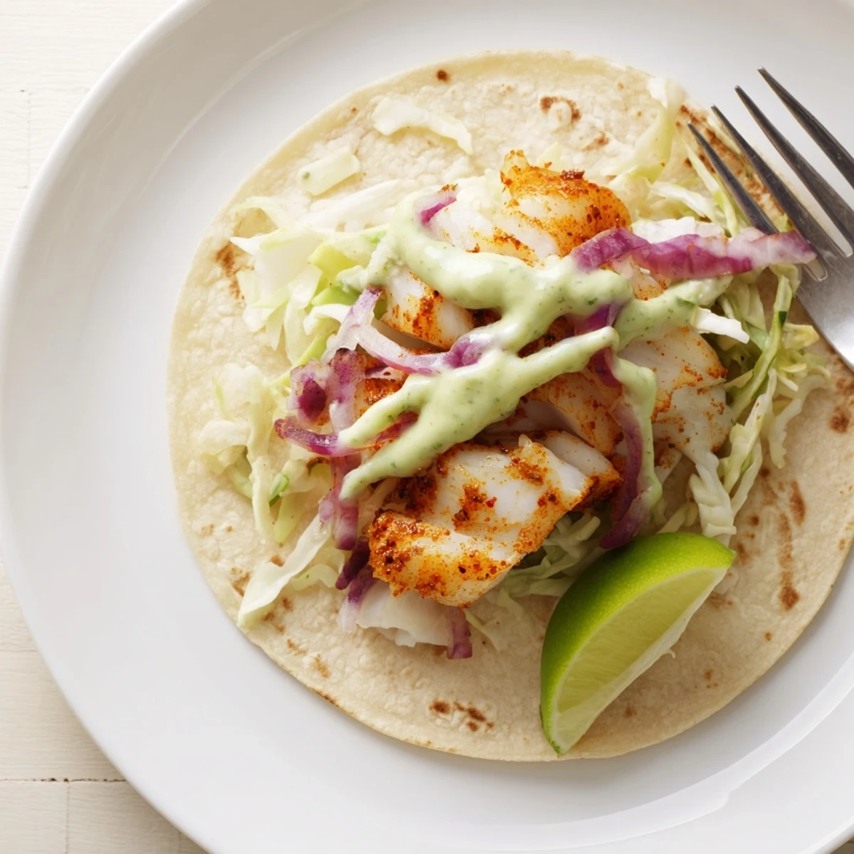 Plated Baked Cod Fish Tacos with Creamy Cilantro Lime Sauce, avocado and lime