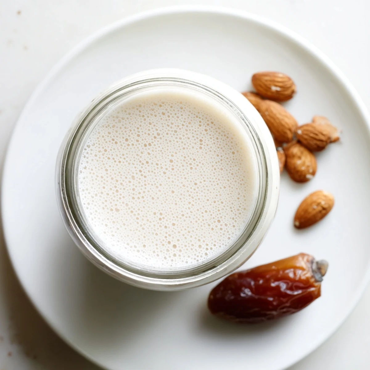 Creamy homemade Almond Milk in glass jar, frothy top, chilled for coffee