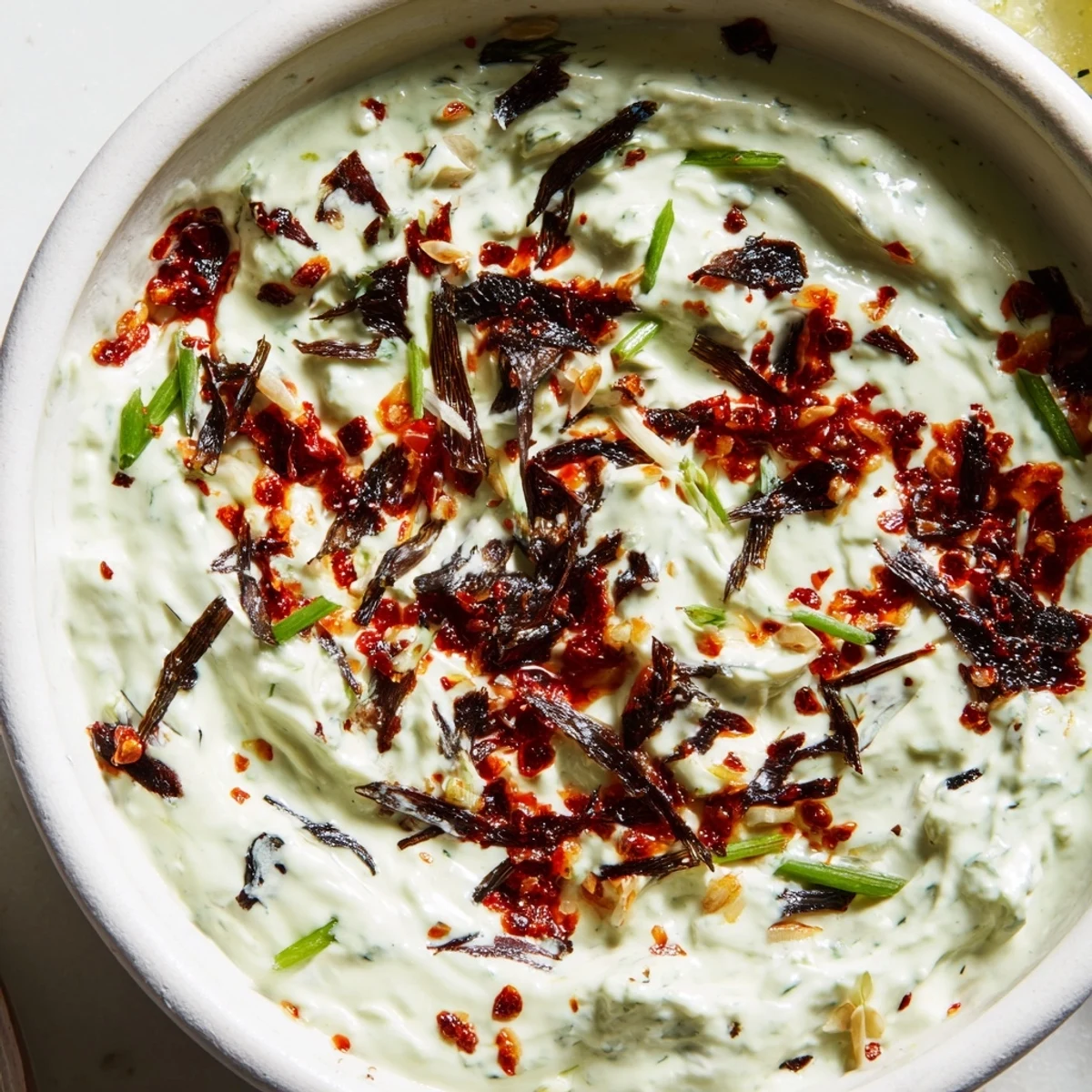 Vibrant charred scallion and chili crisp dip topped with fresh green onion slices