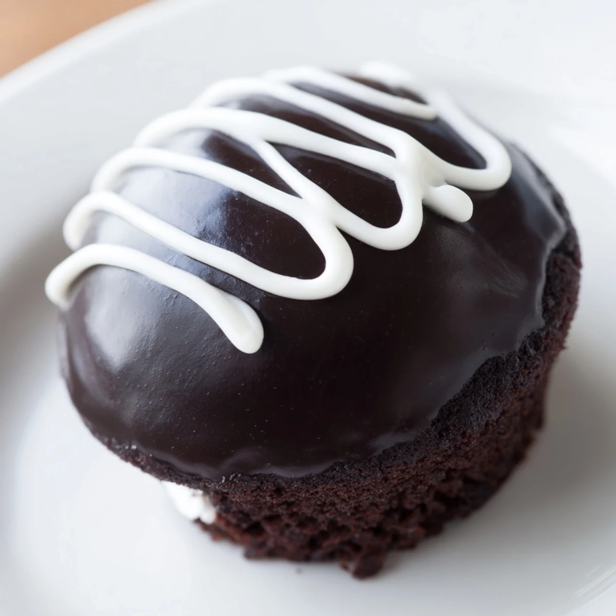 Decadent Homemade Hostess Cupcakes topped with shiny ganache and iconic squiggly white swirl
