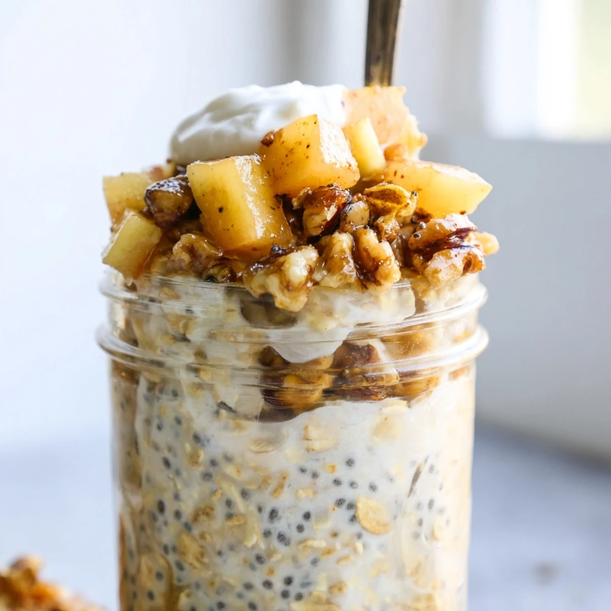 Warm spiced apple crumble overnight oats served in a jar with crunchy walnut topping