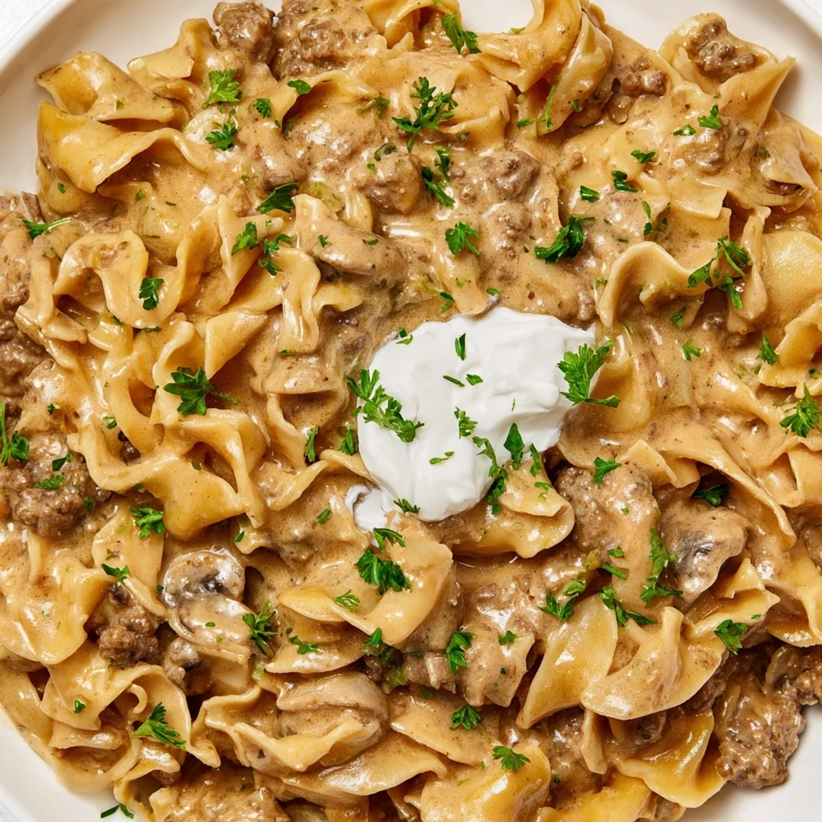 Creamy hamburger stroganoff served over tender egg noodles with fresh parsley garnish
