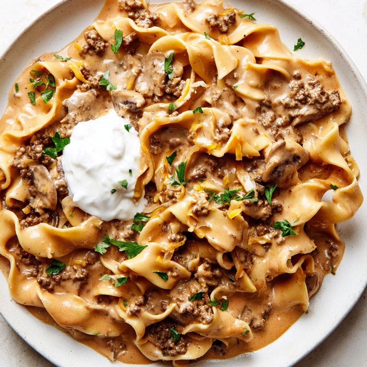 Golden ground beef and mushroom hamburger stroganoff topped with chopped parsley in a bowl