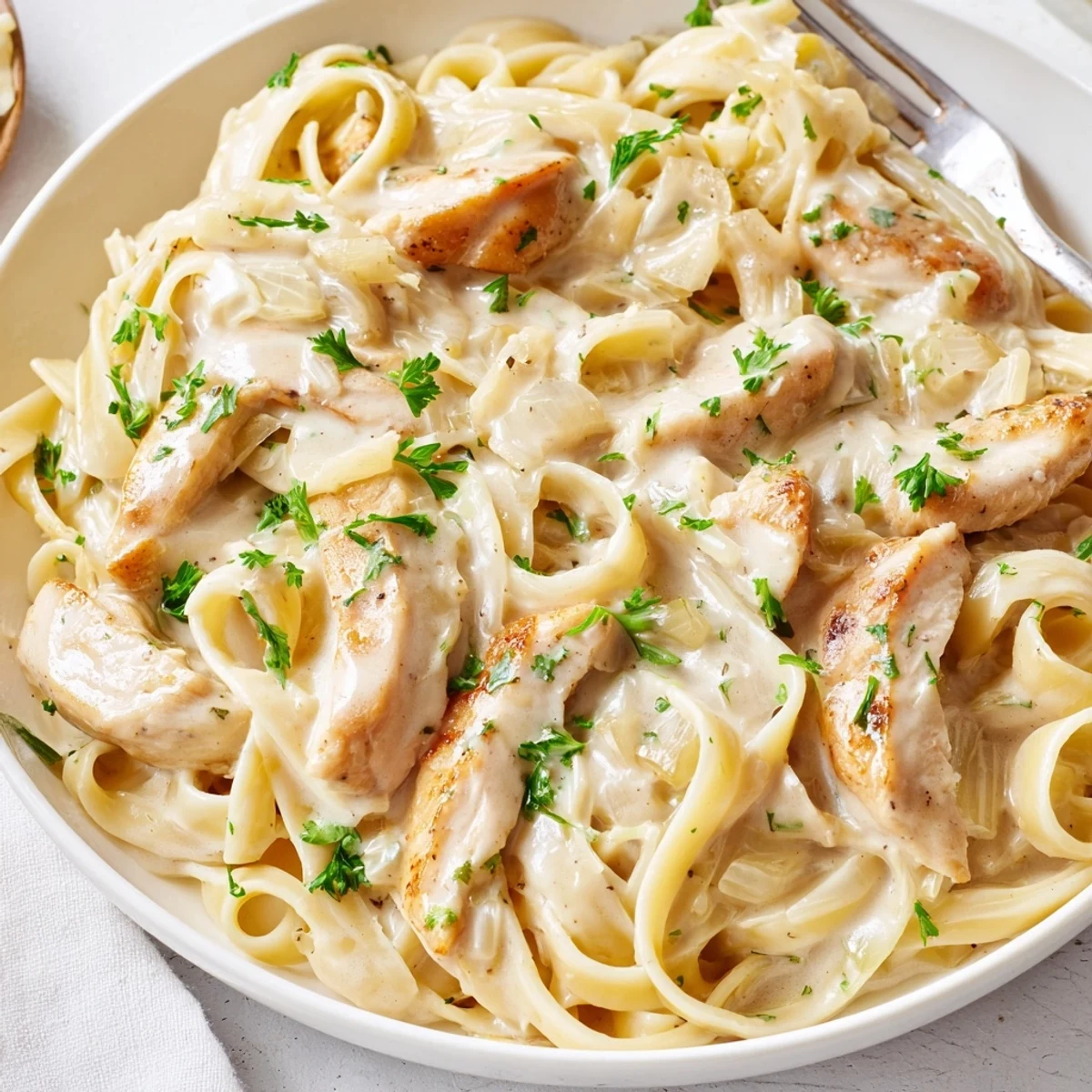 Steaming bowl of creamy garlic Parmesan chicken pasta topped with fresh parsley