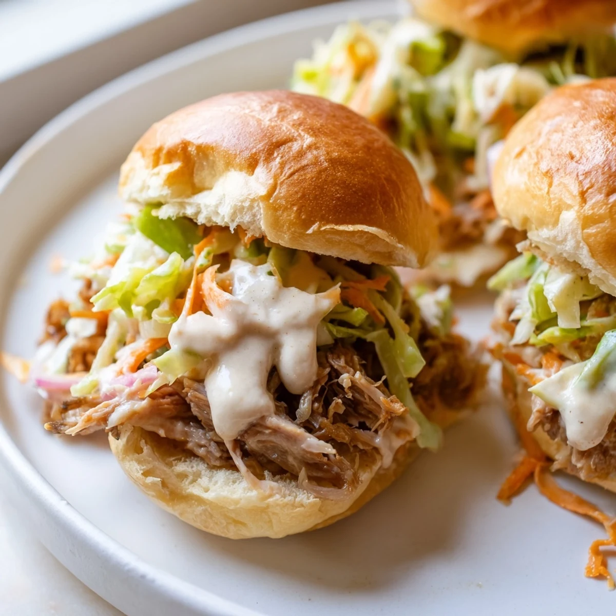Creamy Alabama white sauce pulled lamb sliders topped with crisp cabbage and pickled onions