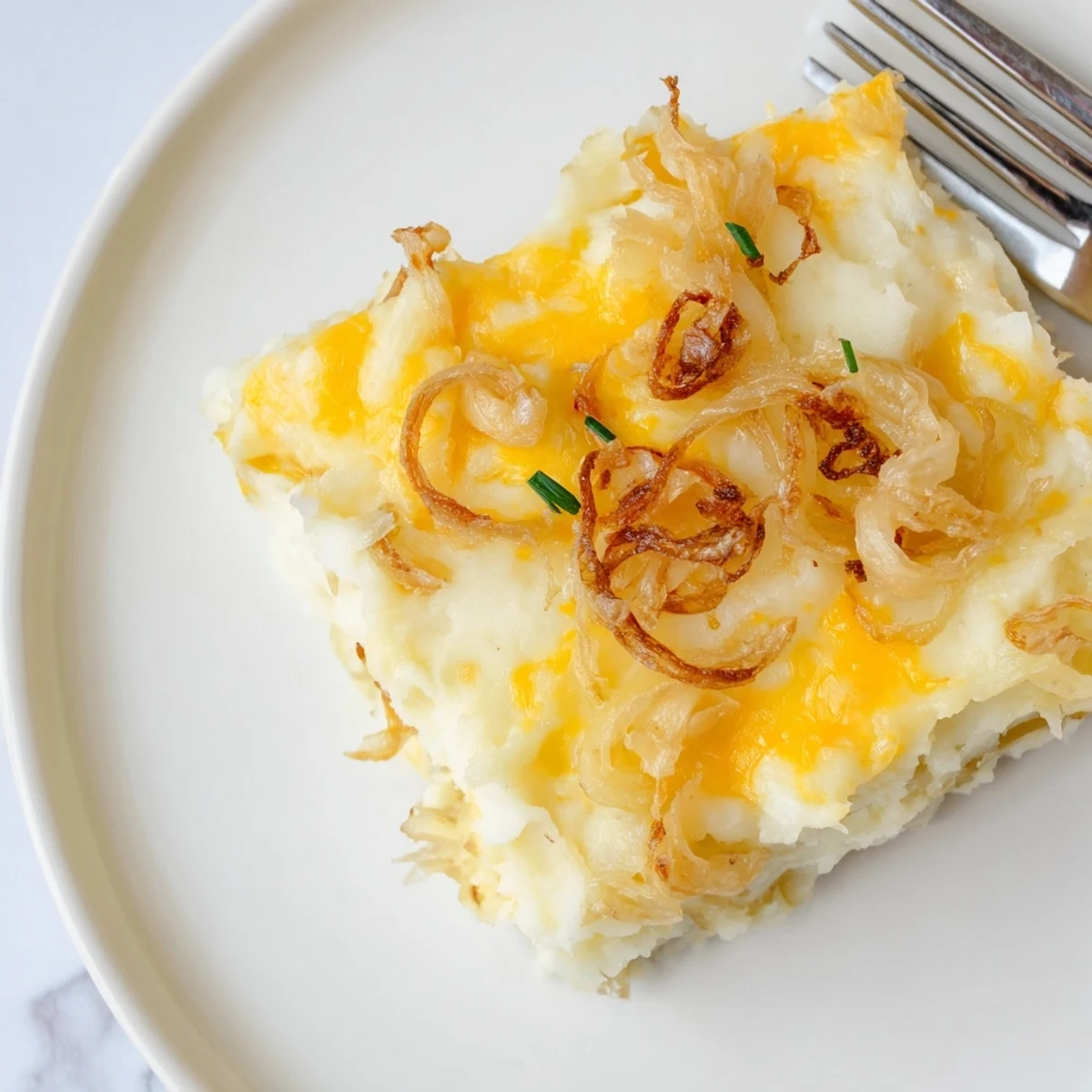 Creamy cheesy onion mashed potato casserole topped with bubbly golden cheddar in a baking dish