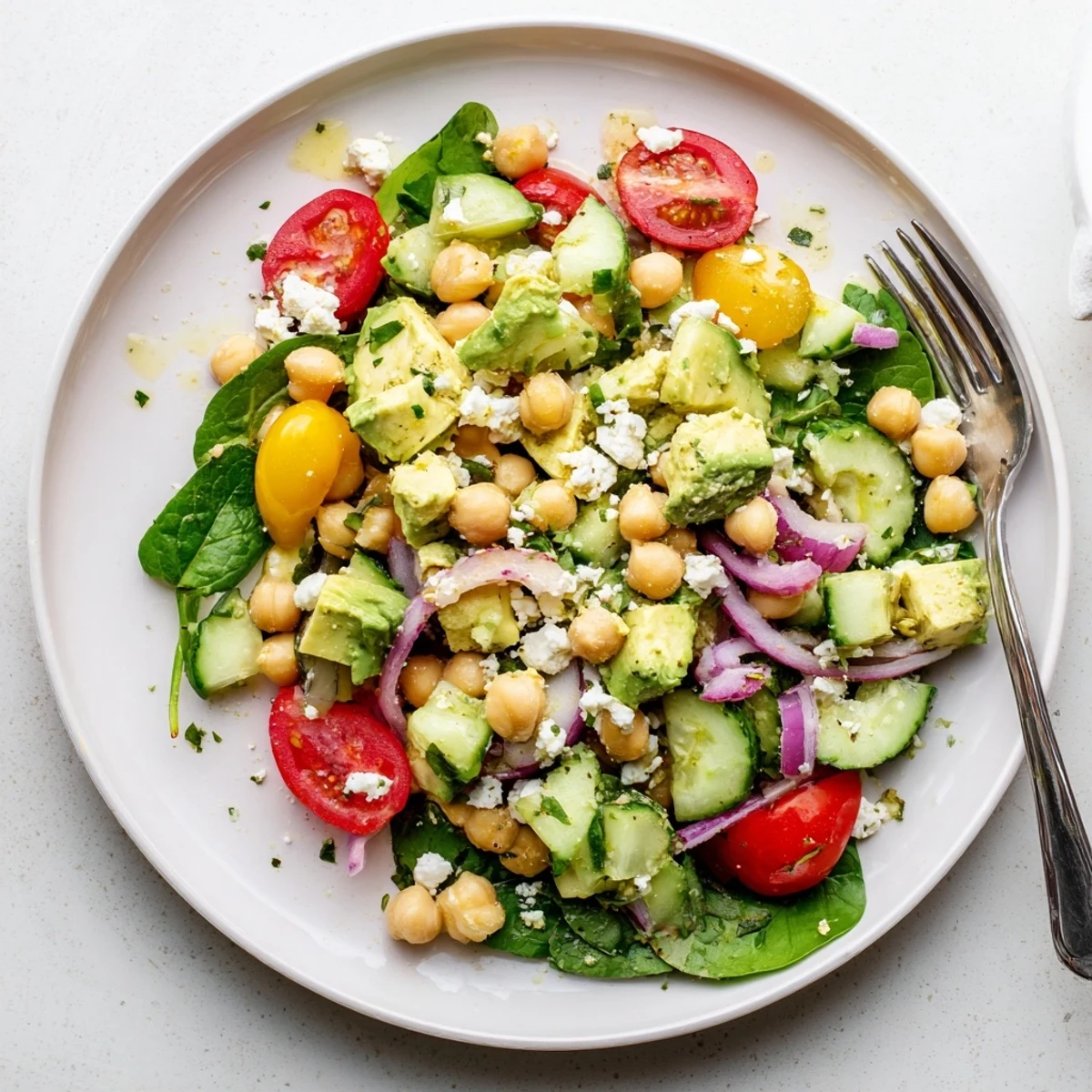 Creamy chickpea feta avocado salad in a rustic bowl with lemon dressing drizzle
