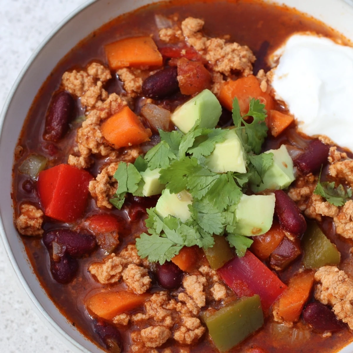 Steaming bowl of diabetic chili recipe topped with avocado and fresh cilantro
