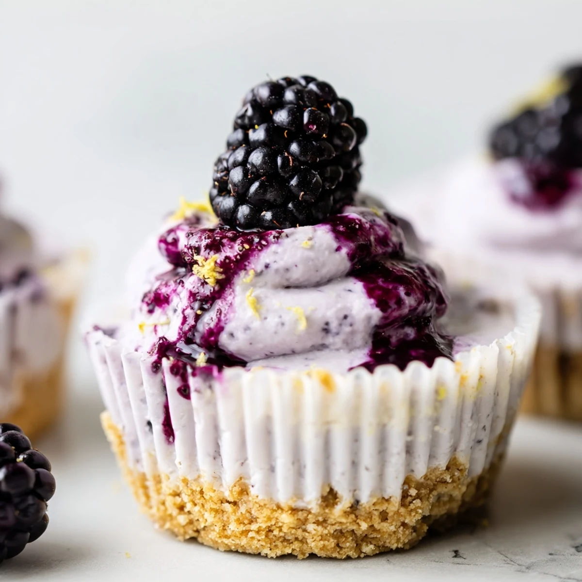Mini Blackberry Lavender Cheesecakes topped with glossy berry sauce in muffin liners