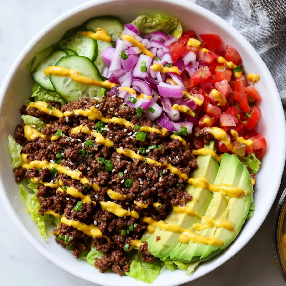 Colorful burger bowls with seasoned ground beef, fresh veggies, and melted cheddar cheese on crisp lettuce