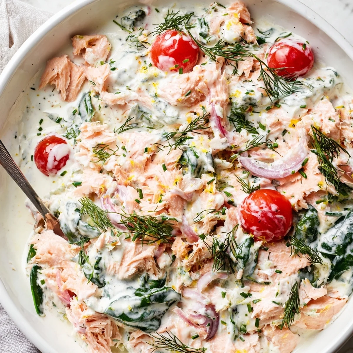 Healthy creamy leftover salmon recipe spooned over quinoa with wilted spinach and cherry tomatoes
