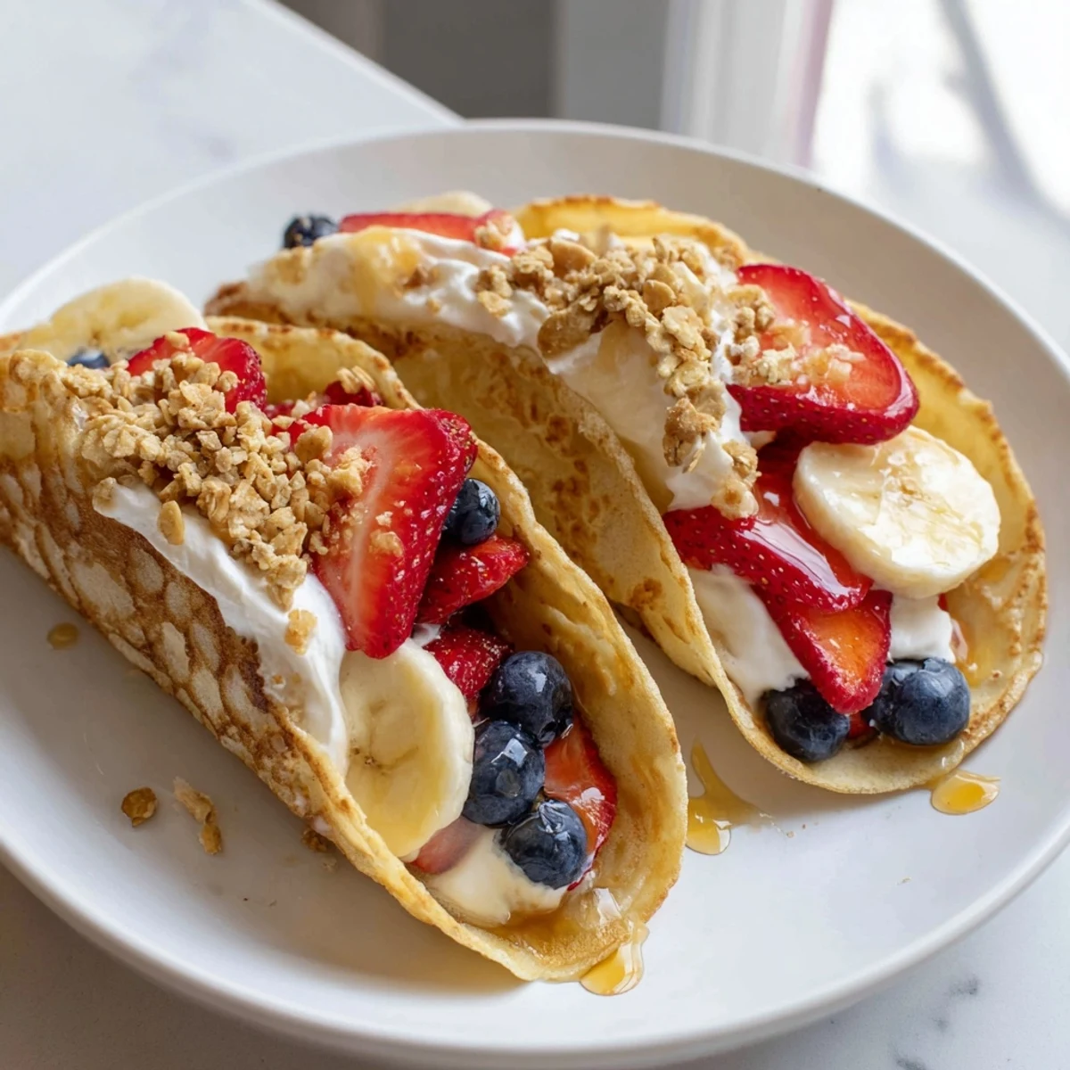 Golden fluffy pancake tacos filled with fresh strawberries, yogurt, and a maple syrup drizzle.