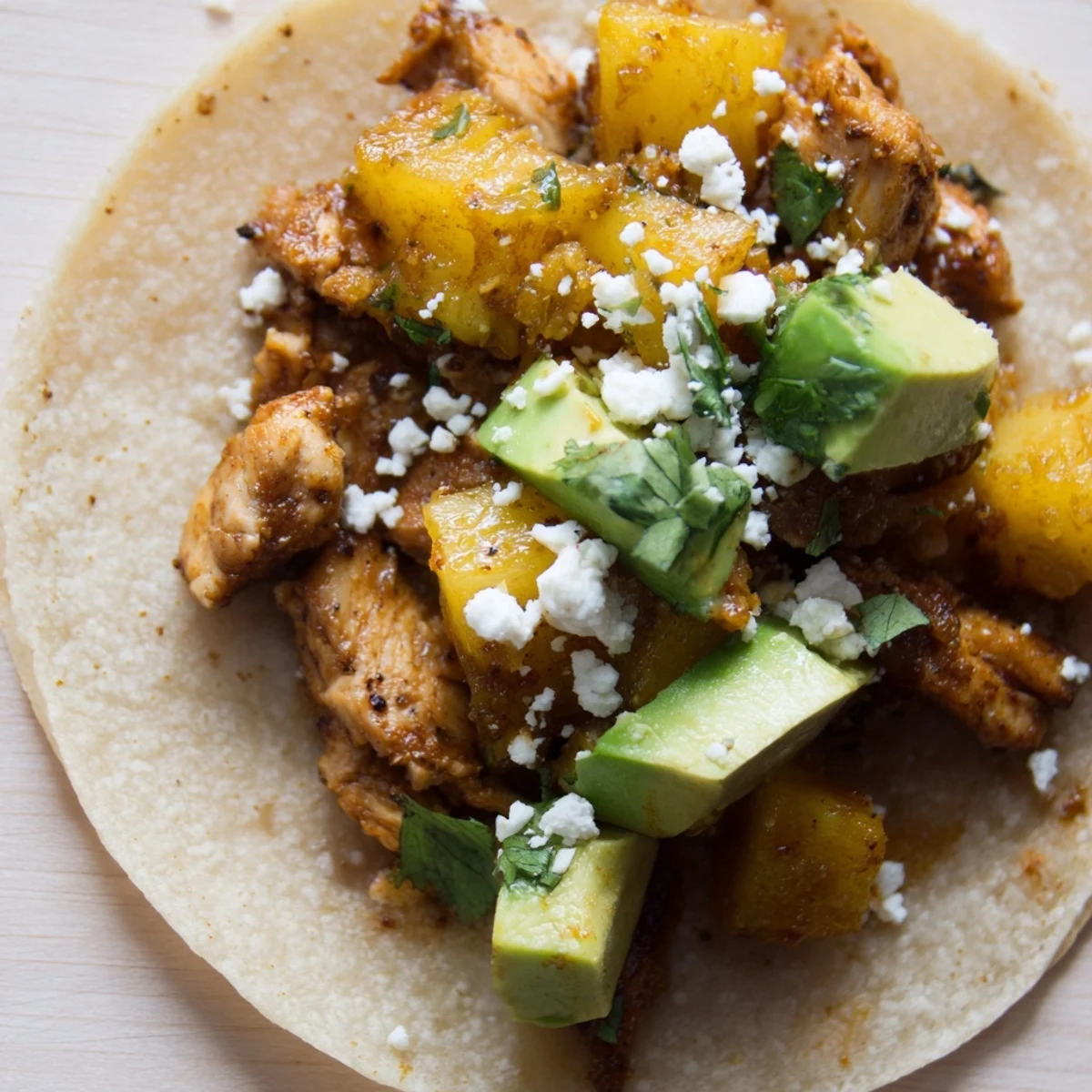 Delicious one pan chicken and pineapple tacos topped with avocado and cilantro.