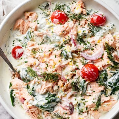 Healthy creamy leftover salmon recipe spooned over quinoa with wilted spinach and cherry tomatoes